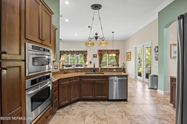 641 Donald Ross Way, Saint Augustine, FL 32092 - kitchen featuring stainless steel appliances, a peninsula, dark stone counters, decorative light fixtures, and crown molding