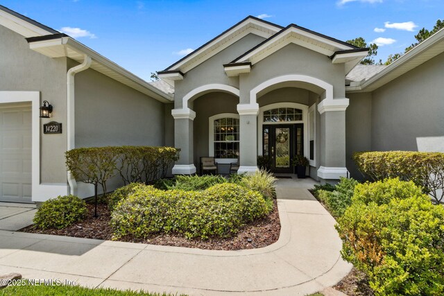 14220 Palmetto Springs St, Jacksonville, FL 32258 - view of exterior entry featuring stucco siding, an attached garage, and covered porch