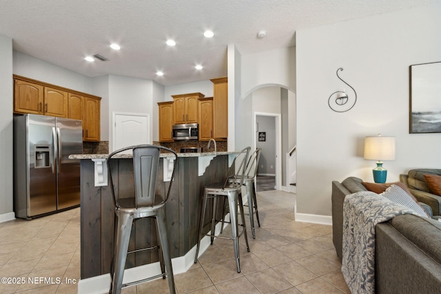 14220 Palmetto Springs St, Jacksonville, FL 32258 - kitchen featuring stainless steel appliances, open floor plan, arched walkways, a kitchen bar, and recessed lighting