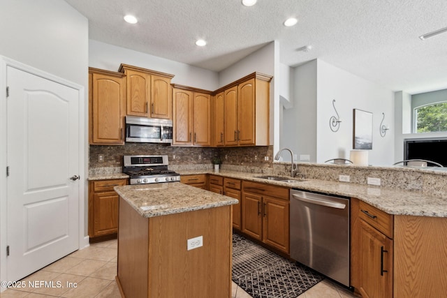 14220 Palmetto Springs St, Jacksonville, FL 32258 - kitchen featuring stainless steel appliances, backsplash, a kitchen island, light stone counters, and a textured ceiling