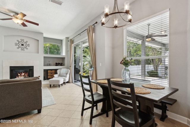 14220 Palmetto Springs St, Jacksonville, FL 32258 - dining room featuring a tiled fireplace, light tile patterned floors, a chandelier, ceiling fan, and a textured ceiling
