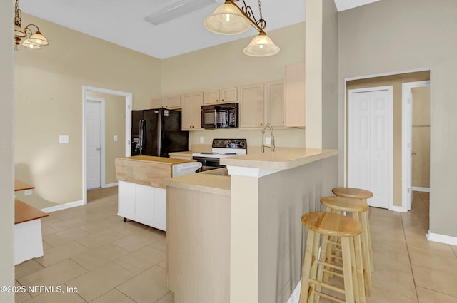 1908 Longneedle Ln, Middleburg, FL 32068 - kitchen with black appliances, light tile patterned floors, light countertops, a kitchen bar, and a peninsula