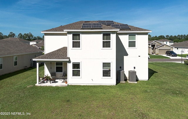 8657 Lake George Cir E, Macclenny, FL 32063 - back of house with roof with shingles, a lawn, roof mounted solar panels, and a patio area