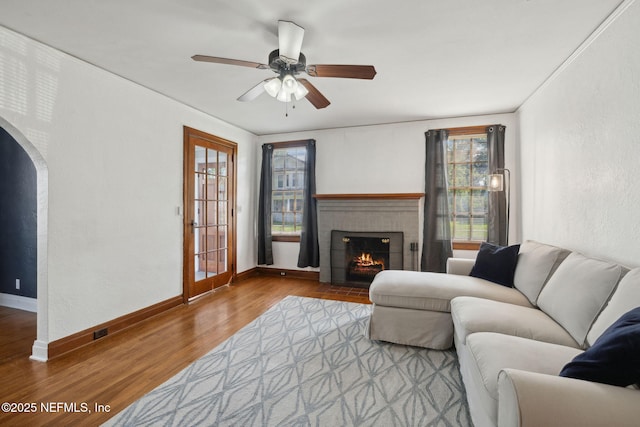1094 Wolfe St, Jacksonville, FL 32205 - living room featuring wood finished floors, a fireplace, ceiling fan, and arched walkways