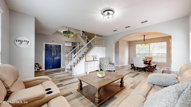 1441 Laurel Oak Dr, Fleming Island, FL 32003 - living room with arched walkways, light wood-style flooring, stairway, a chandelier, and baseboards