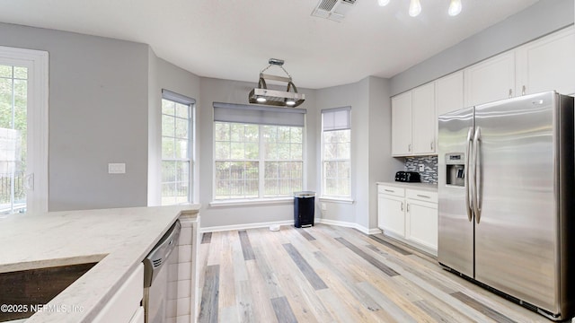 1441 Laurel Oak Dr, Fleming Island, FL 32003 - kitchen with appliances with stainless steel finishes, light wood-type flooring, white cabinetry, light stone countertops, and decorative backsplash