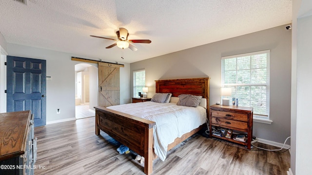 1441 Laurel Oak Dr, Fleming Island, FL 32003 - bedroom with a barn door, wood finished floors, baseboards, and a textured ceiling