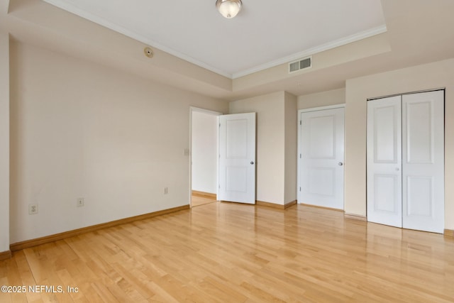 400 E Bay St Unit 401, Jacksonville, FL 32202 - unfurnished bedroom with ornamental molding, light wood-style floors, a closet, and a raised ceiling