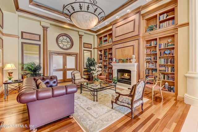 400 E Bay St Unit 401, Jacksonville, FL 32202 - sitting room with ornate columns, a warm lit fireplace, built in shelves, ornamental molding, and light wood-style floors