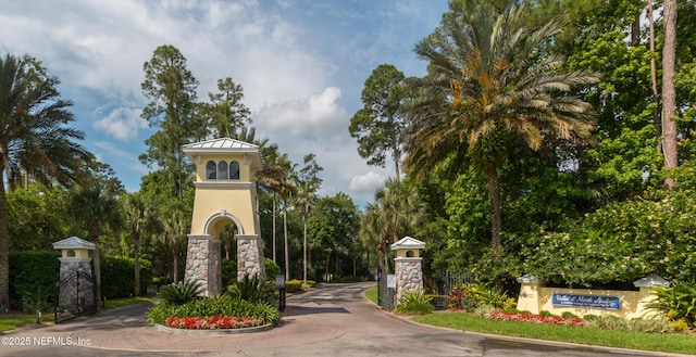 1800 The Greens Way Unit 603, Jacksonville Beach, FL 32250 - view of asphalt street featuring a gated entry, curbs, and view of wooded area