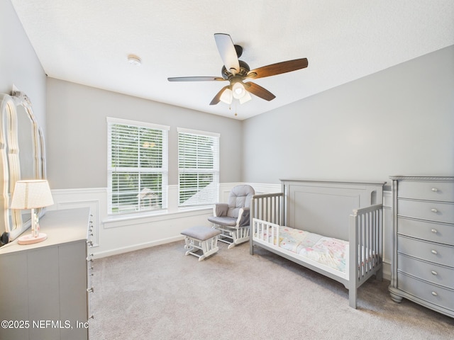 96168 High Pointe Dr, Fernandina Beach, FL 32034 - carpeted bedroom with a ceiling fan, a crib, and a wainscoted wall