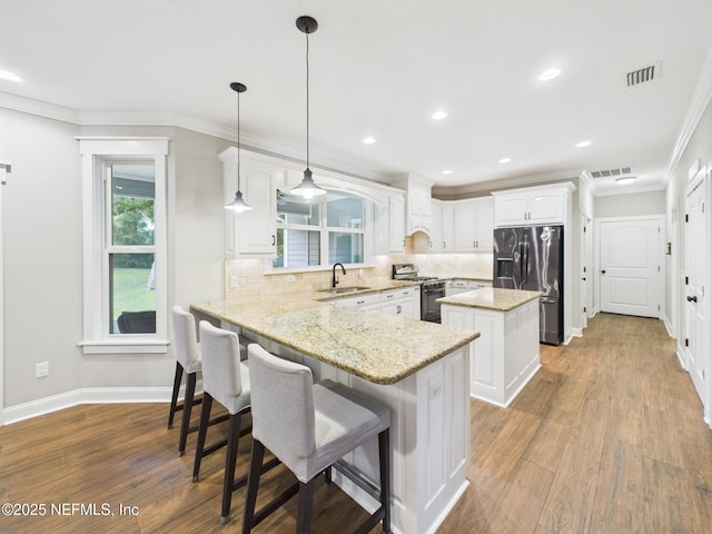 96168 High Pointe Dr, Fernandina Beach, FL 32034 - kitchen with appliances with stainless steel finishes, a peninsula, dark wood-style flooring, a kitchen island, and white cabinetry