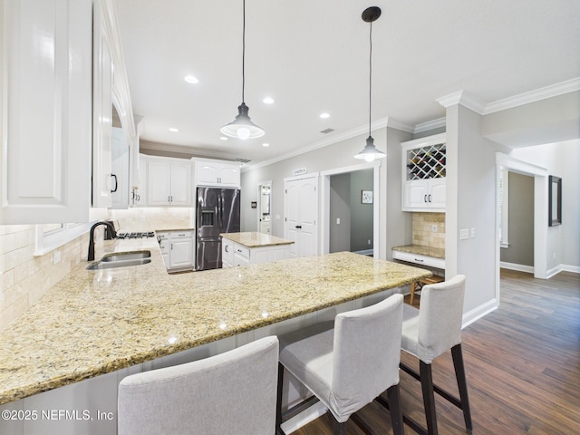 96168 High Pointe Dr, Fernandina Beach, FL 32034 - kitchen with stainless steel fridge, crown molding, decorative backsplash, white cabinets, and light stone countertops