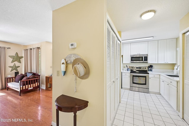 3960 A1A S Unit 505, Saint Augustine Beach, FL 32080 - kitchen featuring stainless steel appliances, a textured ceiling, light countertops, white cabinetry, and light wood-type flooring