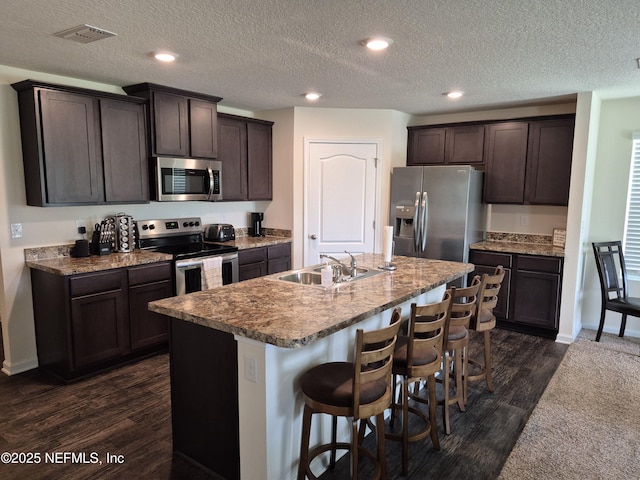2420 Cold Stream Ln, Green Cove Springs, FL 32043 - kitchen featuring appliances with stainless steel finishes, a sink, dark brown cabinets, dark wood-style floors, and a breakfast bar area
