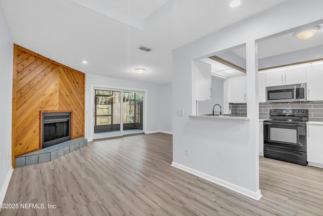 9360 Craven Rd Unit 703, Jacksonville, FL 32257 - kitchen with stainless steel microwave, black electric range oven, white cabinetry, tasteful backsplash, and a fireplace