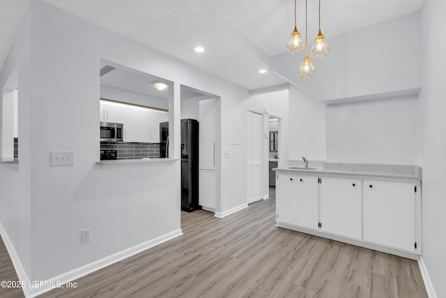 9360 Craven Rd Unit 703, Jacksonville, FL 32257 - kitchen with stainless steel microwave, light wood finished floors, recessed lighting, freestanding refrigerator, and white cabinetry