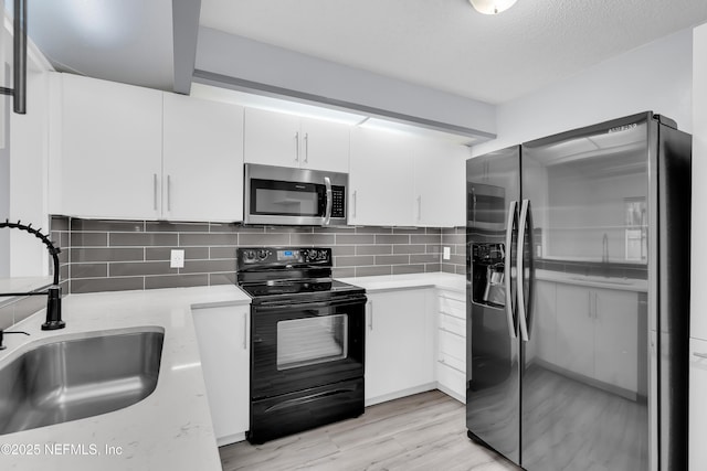 9360 Craven Rd Unit 703, Jacksonville, FL 32257 - kitchen with stainless steel appliances, white cabinetry, decorative backsplash, and light wood-type flooring