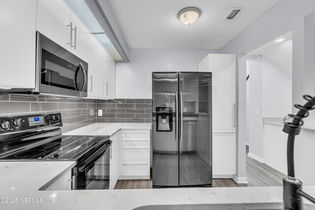 9360 Craven Rd Unit 703, Jacksonville, FL 32257 - kitchen featuring stainless steel appliances, white cabinets, light stone counters, light wood finished floors, and decorative backsplash