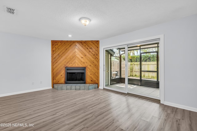 9360 Craven Rd Unit 703, Jacksonville, FL 32257 - unfurnished living room with wood finished floors, a tiled fireplace, a textured ceiling, wood walls, and recessed lighting