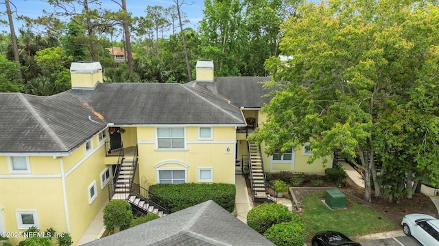 1800 The Greens Way Unit 605, Jacksonville Beach, FL 32250 - view of front of house with stairway, a chimney, stucco siding, and roof with shingles