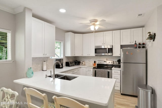 1800 The Greens Way Unit 605, Jacksonville Beach, FL 32250 - kitchen with appliances with stainless steel finishes, a peninsula, tasteful backsplash, light countertops, and white cabinetry