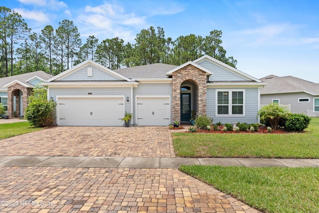 3024 Las Calinas Blvd, Saint Augustine, FL 32095 - view of front of property with decorative driveway, a front lawn, a garage, and stone siding