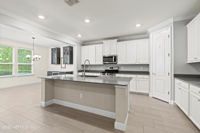 3024 Las Calinas Blvd, Saint Augustine, FL 32095 - kitchen featuring stainless steel appliances, a chandelier, dark countertops, crown molding, and a kitchen island with sink