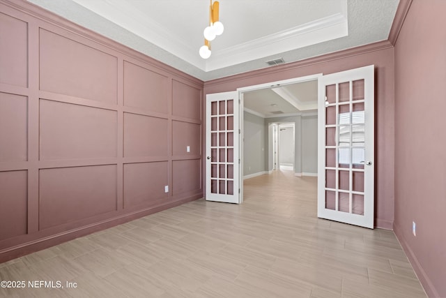 3024 Las Calinas Blvd, Saint Augustine, FL 32095 - empty room featuring french doors, crown molding, a decorative wall, and a raised ceiling