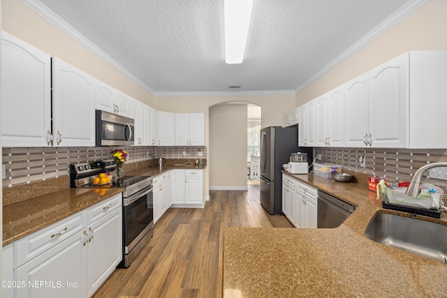 8 Village Cir, Palm Coast, FL 32164 - kitchen with appliances with stainless steel finishes, arched walkways, crown molding, white cabinets, and wood finished floors