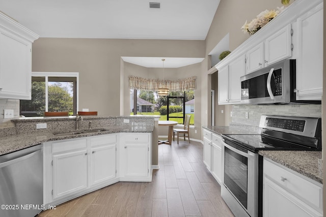 1571 Shelter Cove Dr, Fleming Island, FL 32003 - kitchen with stainless steel appliances, a peninsula, white cabinets, and tasteful backsplash