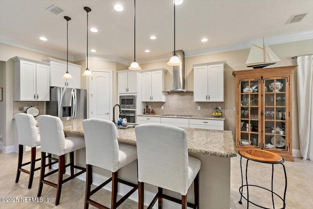 4705 Sawbuck St, Saint Augustine, FL 32092 - kitchen featuring appliances with stainless steel finishes, wall chimney range hood, ornamental molding, decorative backsplash, and a breakfast bar