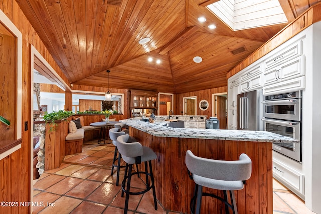 970 Fruit Cove Rd, Saint Johns, FL 32259 - kitchen with lofted ceiling, a skylight, stainless steel appliances, white cabinetry, and a large island
