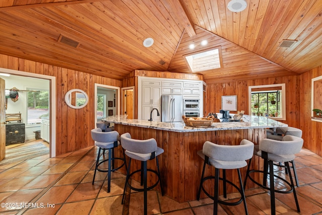 970 Fruit Cove Rd, Saint Johns, FL 32259 - kitchen with wood walls, light stone countertops, a skylight, stainless steel appliances, and white cabinetry
