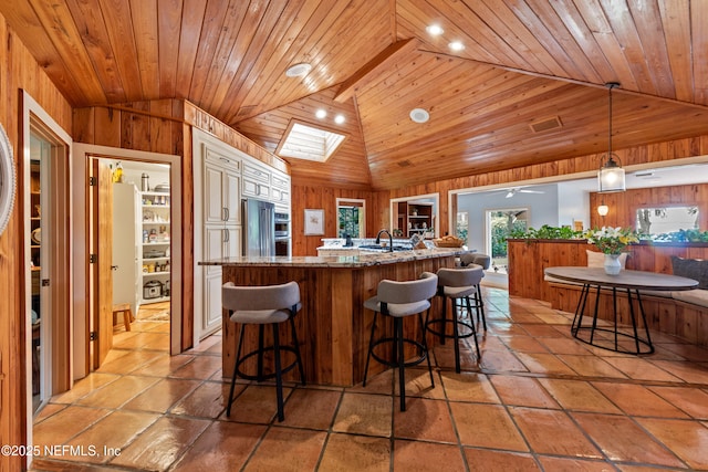 970 Fruit Cove Rd, Saint Johns, FL 32259 - kitchen featuring vaulted ceiling, high end refrigerator, light stone countertops, a skylight, and wood walls