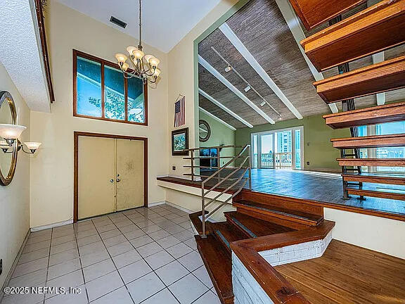 5903 Bimini Way N, Saint Petersburg, FL 33706 - entryway featuring a chandelier, tile patterned flooring, high vaulted ceiling, and stairway