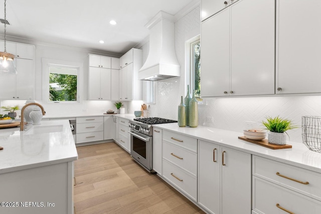1501 Emma Ln, Neptune Beach, FL 32266 - kitchen featuring high end stove, custom exhaust hood, tasteful backsplash, white cabinetry, and light wood-type flooring