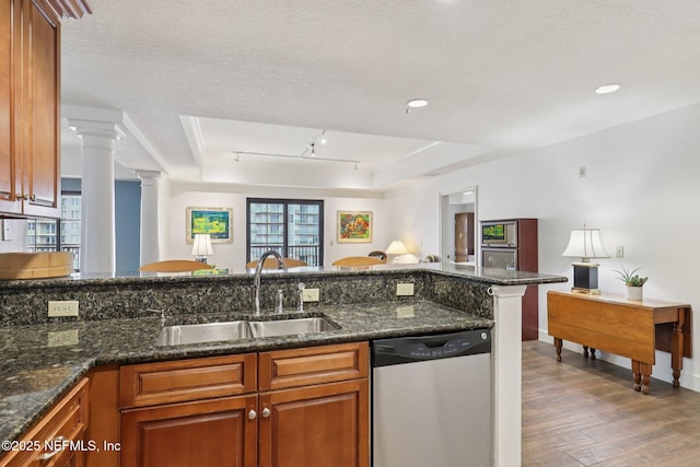 1478 Riverplace Blvd Unit 1605, Jacksonville, FL 32207 - kitchen featuring dishwasher, wood finished floors, brown cabinetry, decorative columns, and dark stone counters