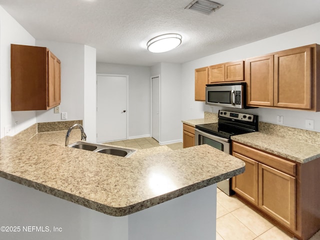 287 Buck Run Way, Saint Augustine, FL 32092 - kitchen with stainless steel appliances, a peninsula, light tile patterned floors, brown cabinets, and a textured ceiling