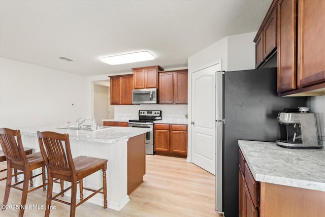 189 Blue Creek Way, Saint Augustine, FL 32086 - kitchen featuring appliances with stainless steel finishes, a kitchen breakfast bar, light wood-style floors, light countertops, and brown cabinets