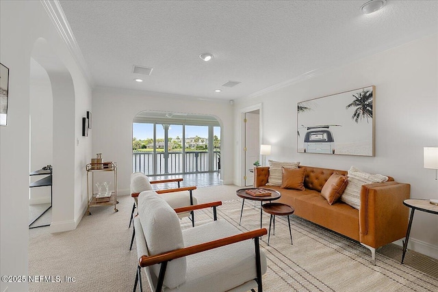 91 San Juan Dr Unit E3, Ponte Vedra Beach, FL 32082 - living room with ornamental molding, arched walkways, a textured ceiling, light colored carpet, and a water view