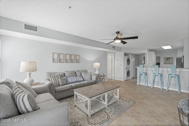 110 Ocean Hollow Ln Unit 114, Saint Augustine, FL 32084 - living room featuring stacked washer / dryer, a textured ceiling, a ceiling fan, and light tile patterned floors