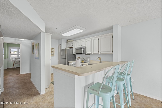 110 Ocean Hollow Ln Unit 114, Saint Augustine, FL 32084 - kitchen with stainless steel appliances, light countertops, a kitchen breakfast bar, a peninsula, and a textured ceiling