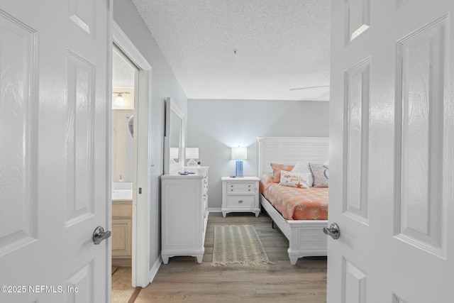 110 Ocean Hollow Ln Unit 114, Saint Augustine, FL 32084 - bedroom with light wood-type flooring, a textured ceiling, and connected bathroom