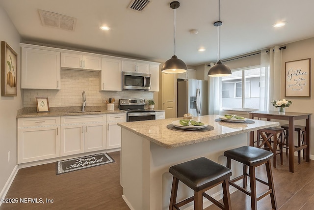 279 Selden Ave, Ormond Beach, FL 32174 - kitchen featuring stainless steel appliances, white cabinetry, decorative backsplash, dark wood-style flooring, and a kitchen island