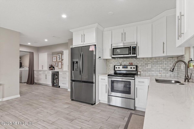 325 Sargo Rd, Atlantic Beach, FL 32233 - kitchen featuring stainless steel appliances, washer / dryer, beverage cooler, white cabinets, and backsplash
