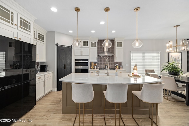 347 Ness Cir, Saint Augustine, FL 32095 - kitchen featuring a barn door, stainless steel double oven, tasteful backsplash, light wood-style floors, and recessed lighting