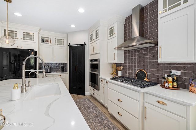 347 Ness Cir, Saint Augustine, FL 32095 - kitchen featuring wall chimney range hood, stainless steel appliances, a barn door, recessed lighting, and decorative backsplash