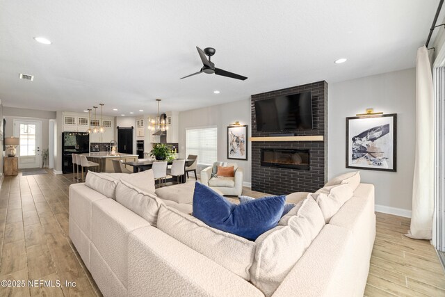 347 Ness Cir, Saint Augustine, FL 32095 - living room with a brick fireplace, ceiling fan, light wood-type flooring, a chandelier, and recessed lighting