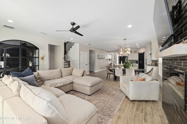 347 Ness Cir, Saint Augustine, FL 32095 - living area featuring light wood-style flooring, stairway, a chandelier, a ceiling fan, and a fireplace